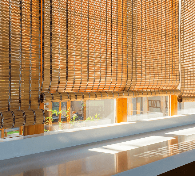Bamboo blinds casting shadows on windowsill.