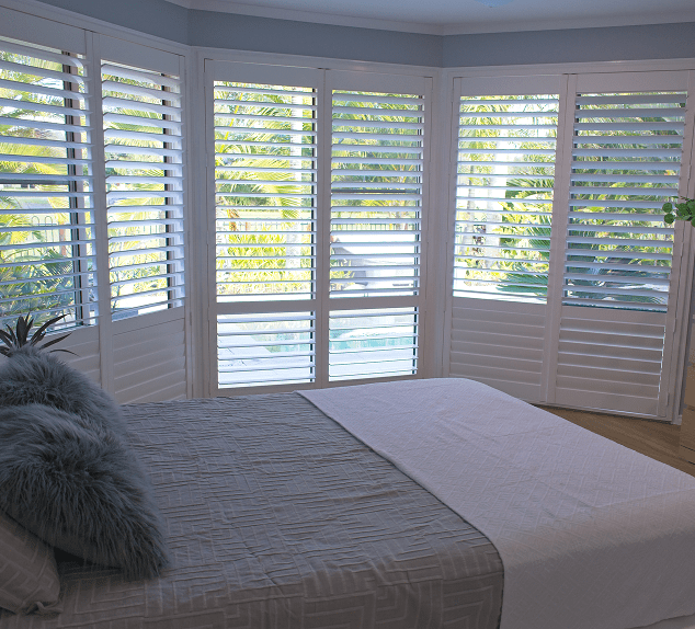 Bedroom with large windows and shutters.