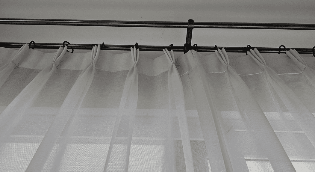 White sheer curtains on metal rod.
