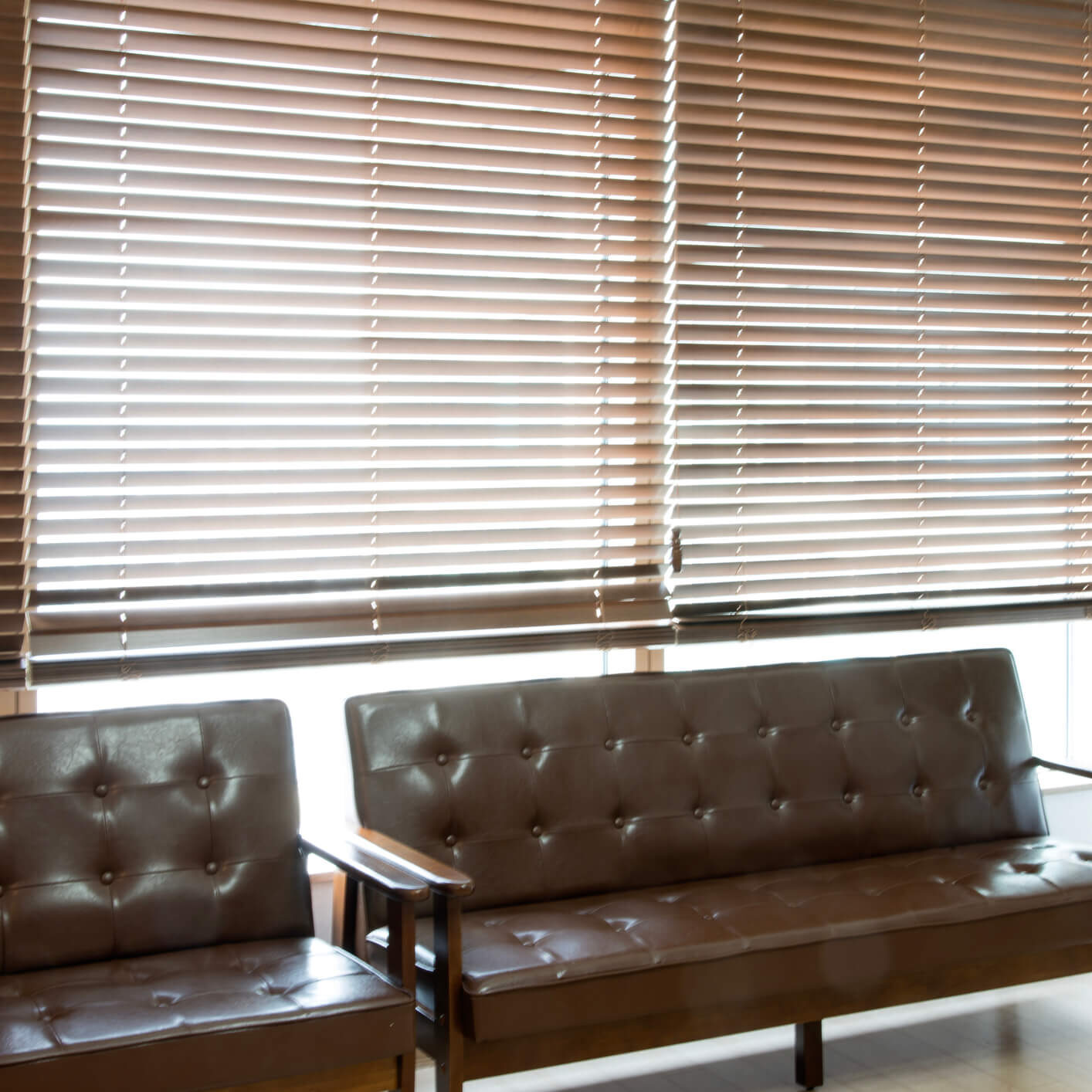 Office lounge with brown sofas and blinds.