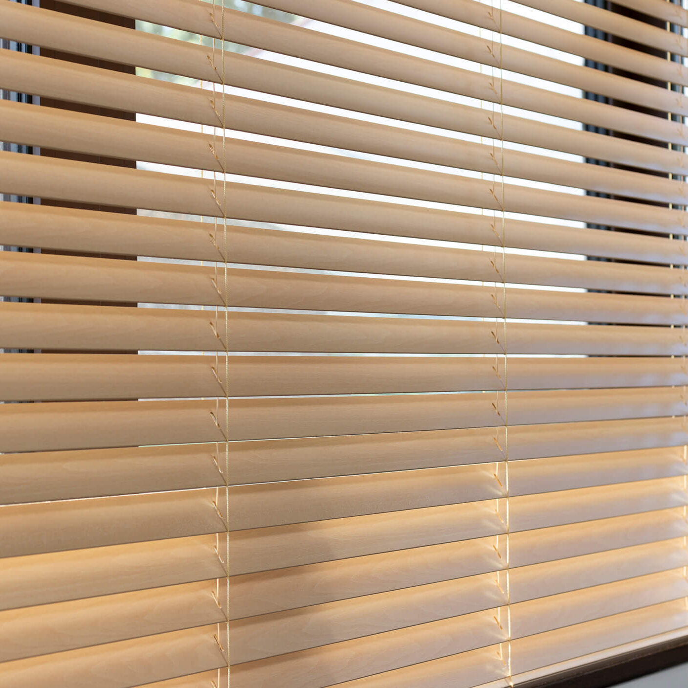 Window blinds partially open with sunlight filtering.